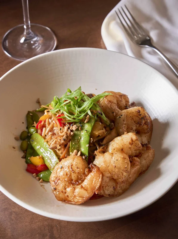 Spicy shrimp noodle bowl with chuka soba noodles, shiitake mushrooms, baby bok choy, carrots, peppers, spicy peanut crumbles, cilantro, and scallions